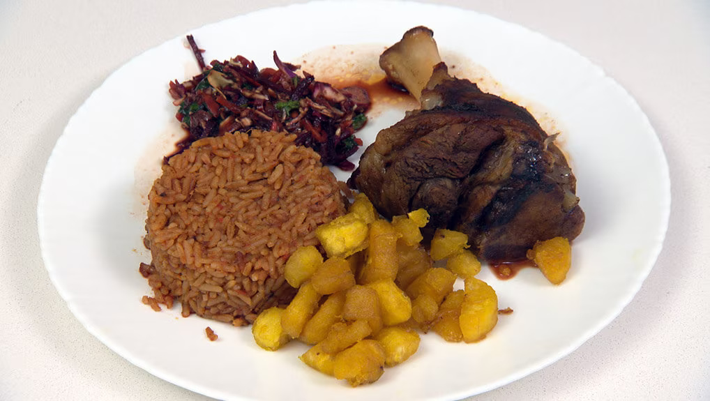Lamb Shank Serviced with Jollof Rice, Plantain and Asian Slaw